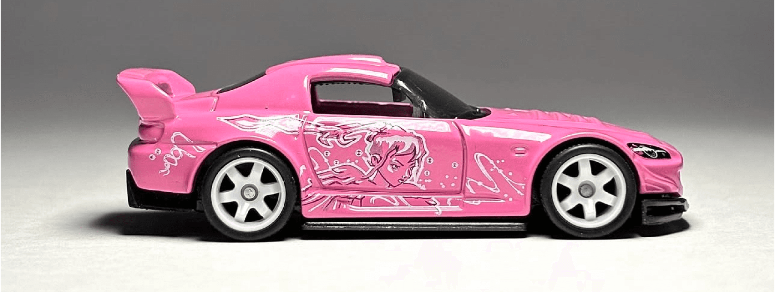 Side profile photograph of a customized sports car with illustrated graphics